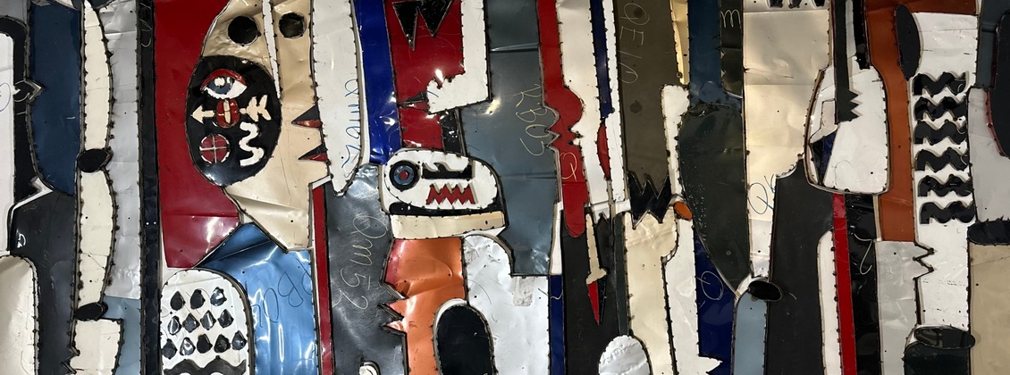 Abstract artwork made from painted, crumpled metal strips, featuring faces, shapes, and bold colors including black, white, red, blue, and orange, arranged vertically with jagged edges and expressive designs.