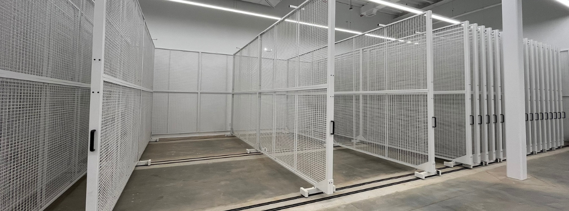 A spacious room with sliding white metal mesh panels on tracks, used for organized storage or display, set on a polished concrete floor under bright overhead lighting.